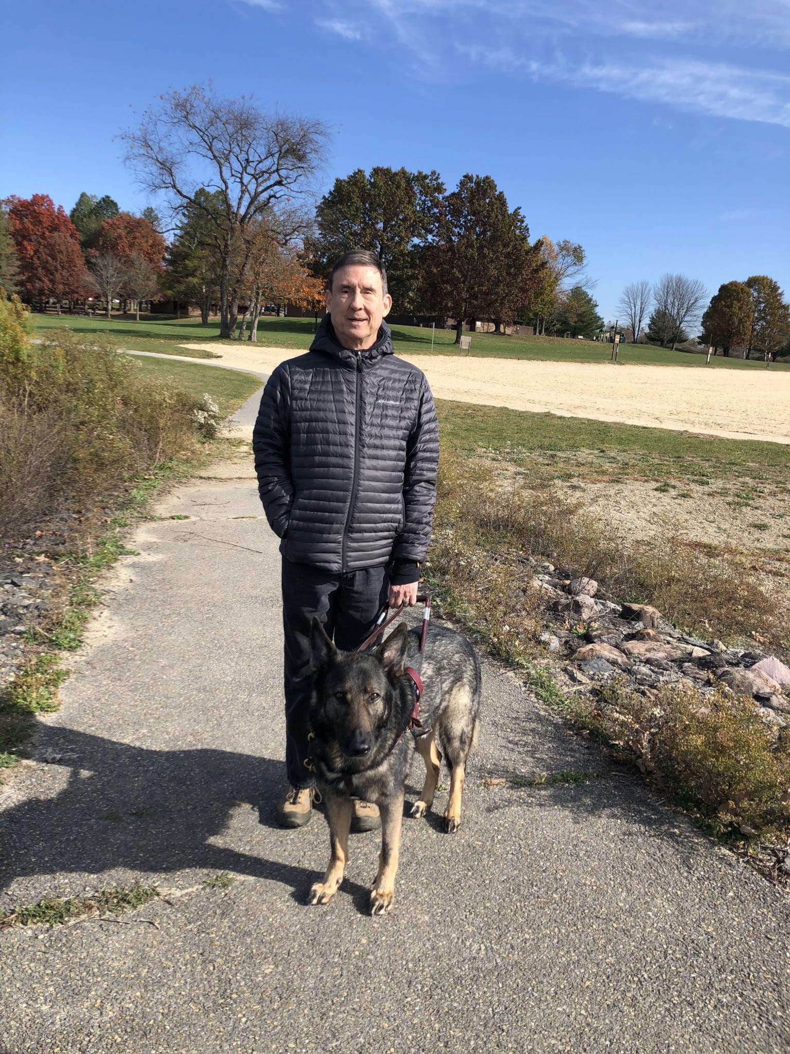 Paul standing holding the harness of cozmo on a sidewalk