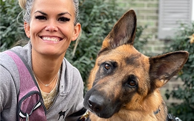 A lovely Fidelco client kneeling down next to her full grown guide dog.