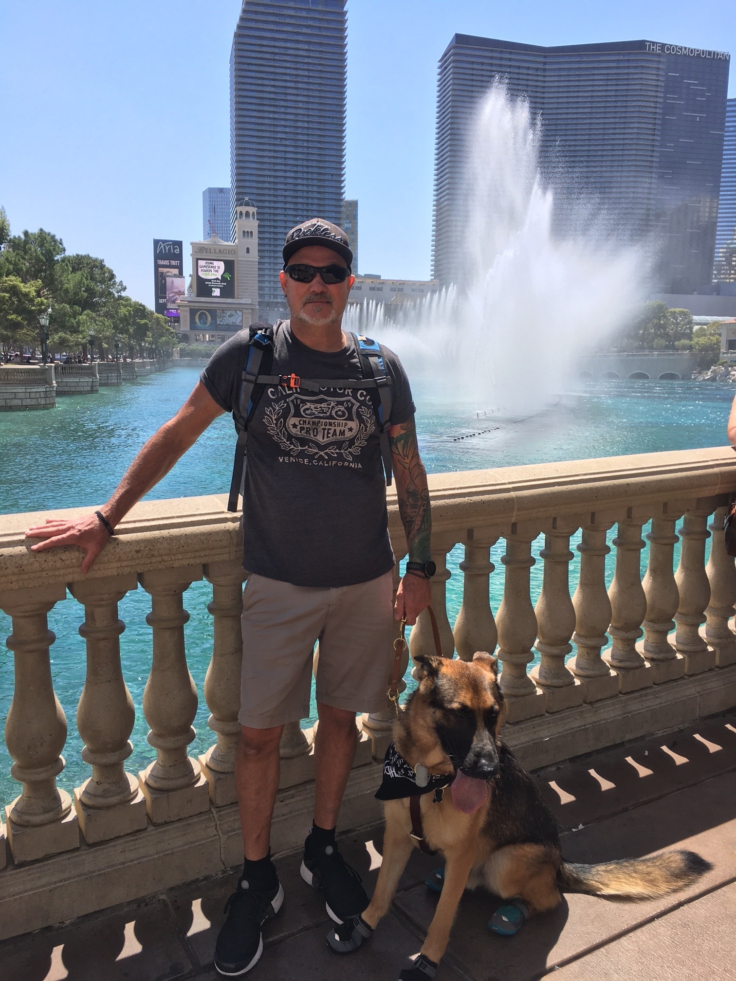 Sean stands in front of a water feature holding the lead of Xavier