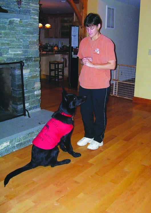 Kim standing with "Kaleb," a black shepherd, in front of her.