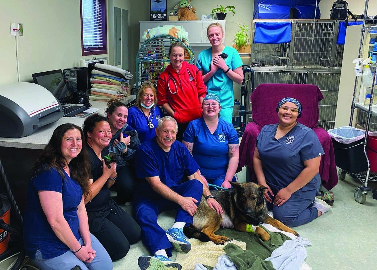 Dr. Arnold Goldman sitting on floor with VetMed staff sitting around him.