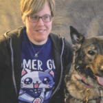 Amy R sitting smiling next her guide dog Olive